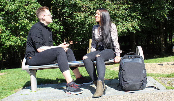 Young man and young woman sitting on a park bench