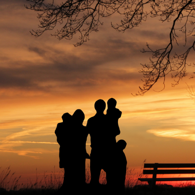 Shadows of a family of five looking out into a sunset