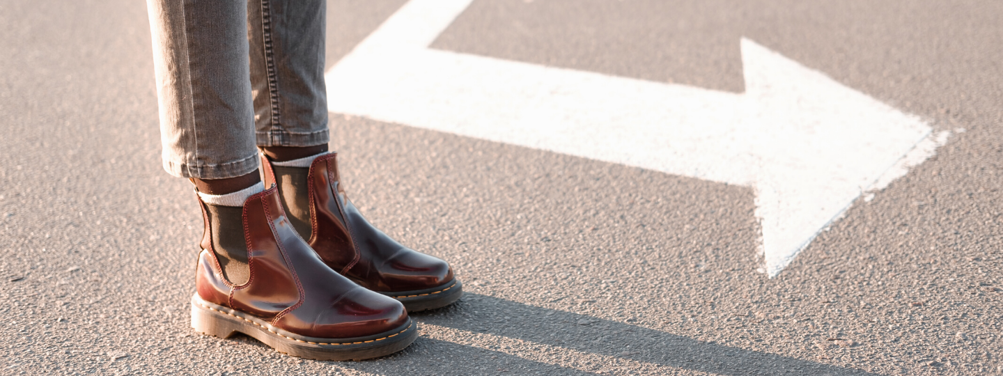 Close up of someone's boots on a road in the direction of an arrow painted on the road