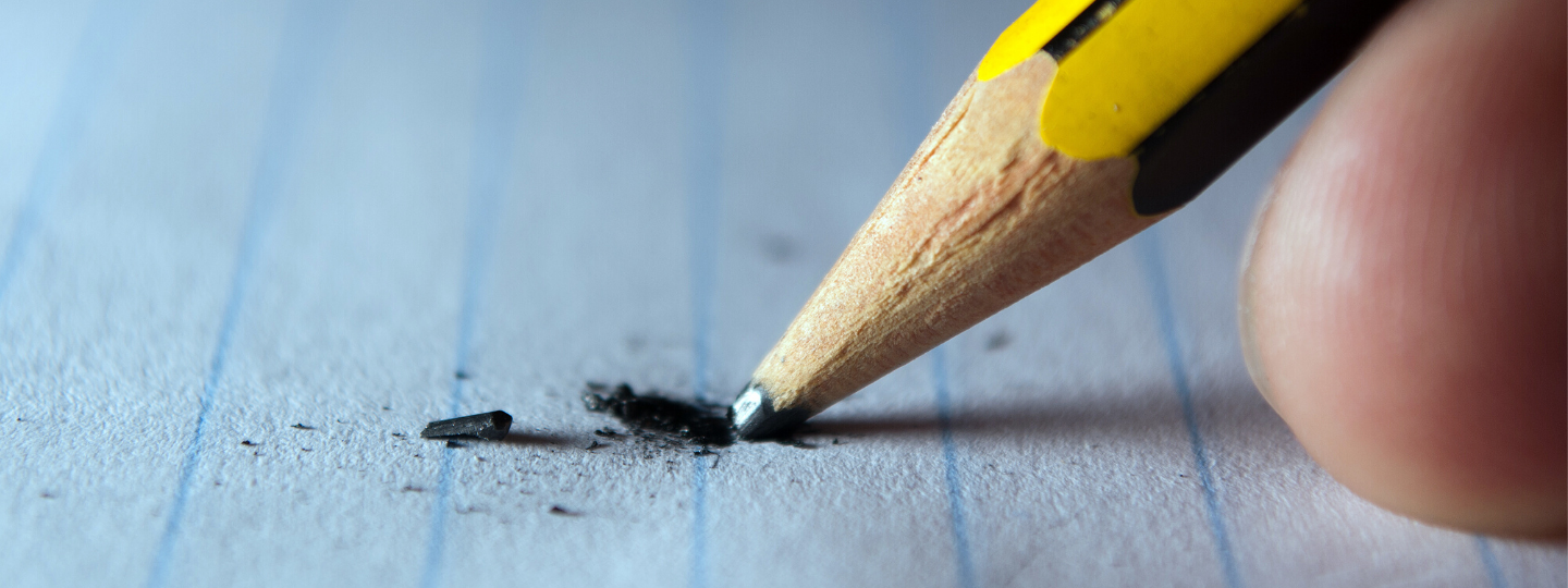 Close up of a pencil being pushed on paper and breaking