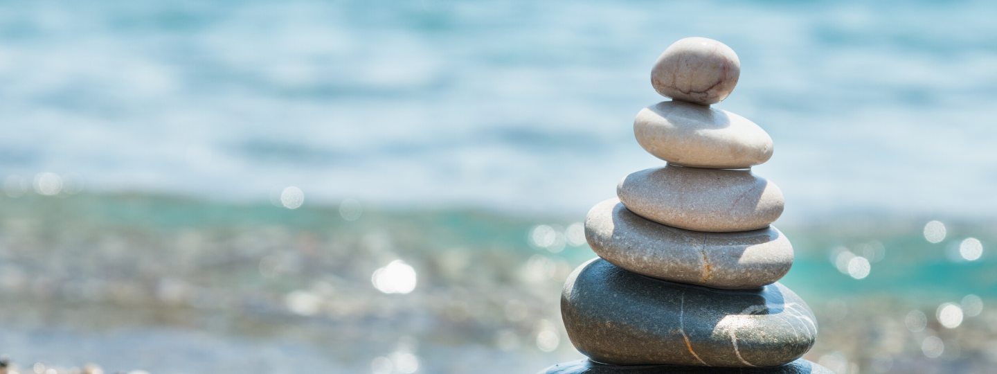 Stacked stones by the water to illustrate relaxation for mental health