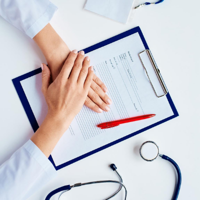 Doctor with hands place on patient form with stethoscope also on table