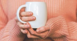 A girl wearing holding a white ceramic mug