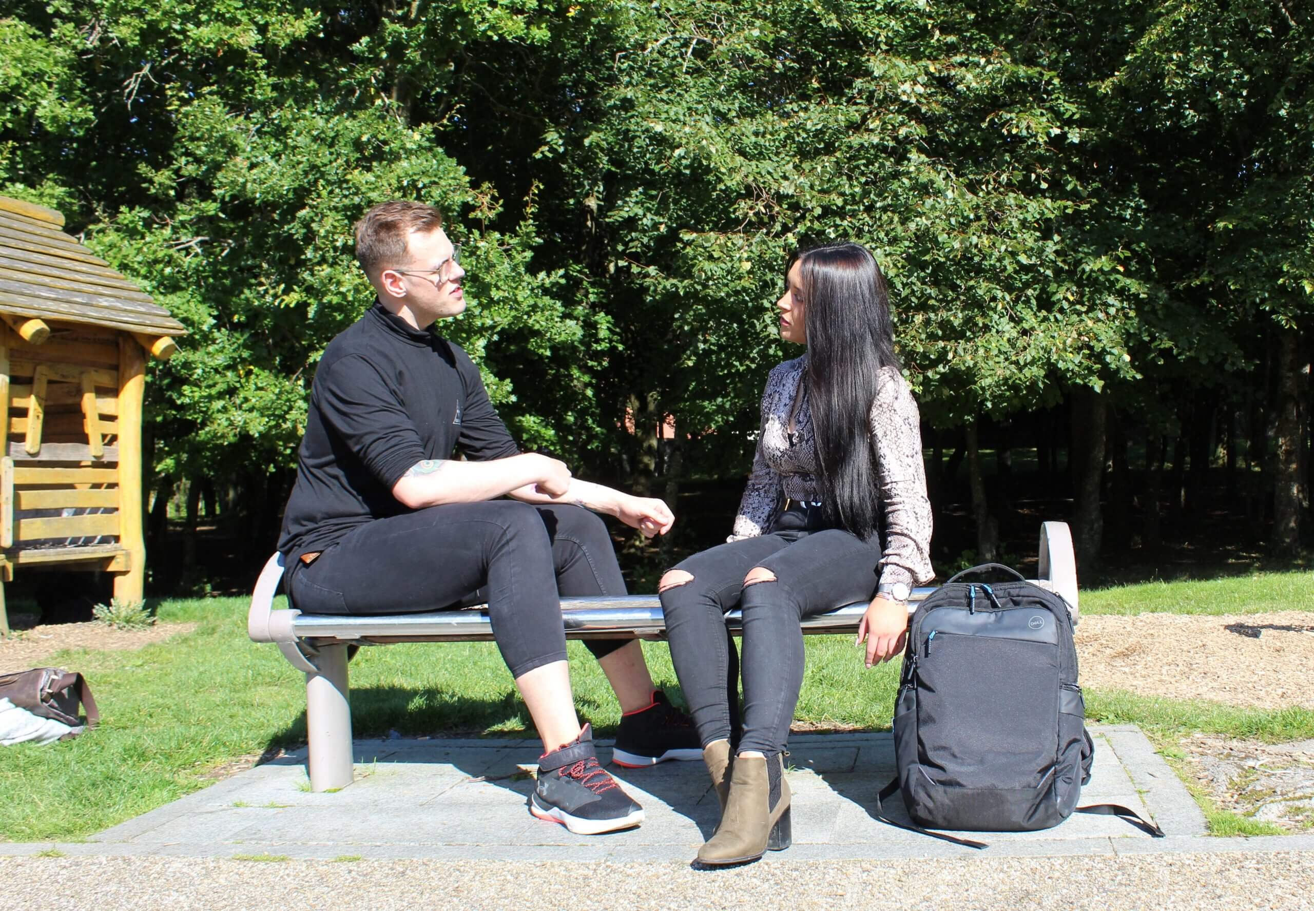 Two young people chatting on a park bench