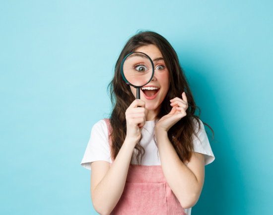 happy young woman looking through magnifying glass