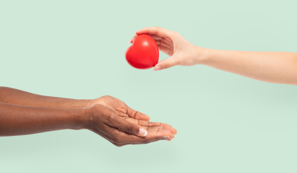 plastic heart in one hand being given to pair of hands