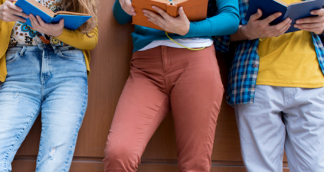 students reading books only visible from their knees to their midriffs