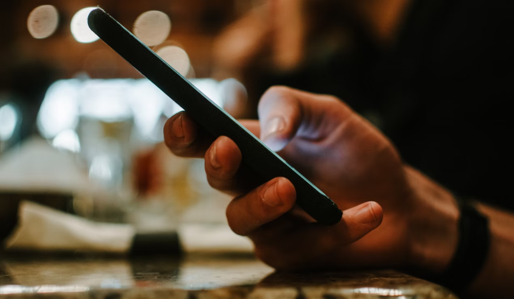 Photograph of a hand texting on a mobile phone.