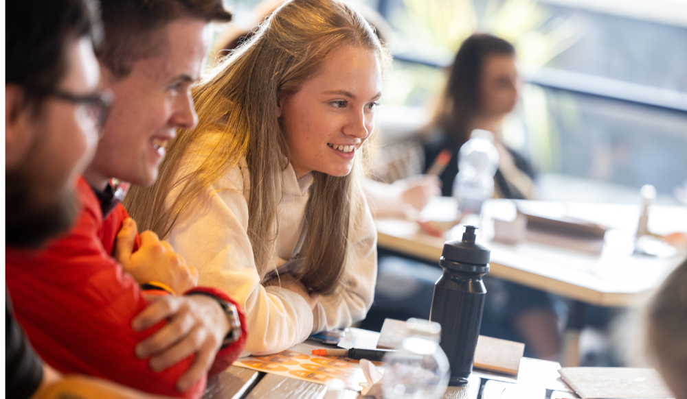 Side profiles of three young people laughing