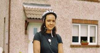 Amina, one of our volunteers in front of her house with cycling helmett