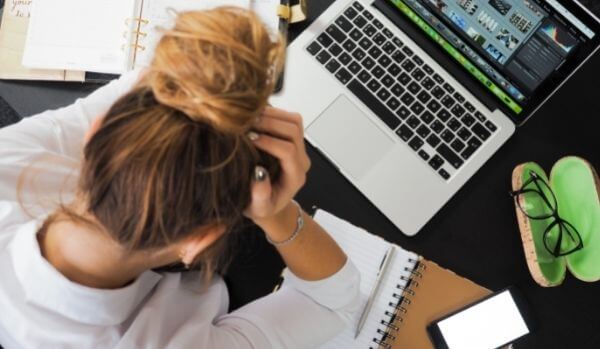 Girl with head in hands studying with laptop and notpads