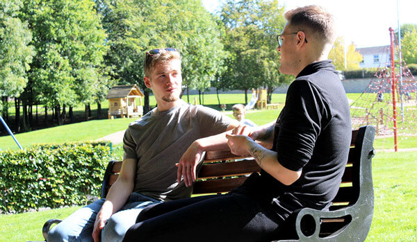 Two young men sitting on a park bench chatting