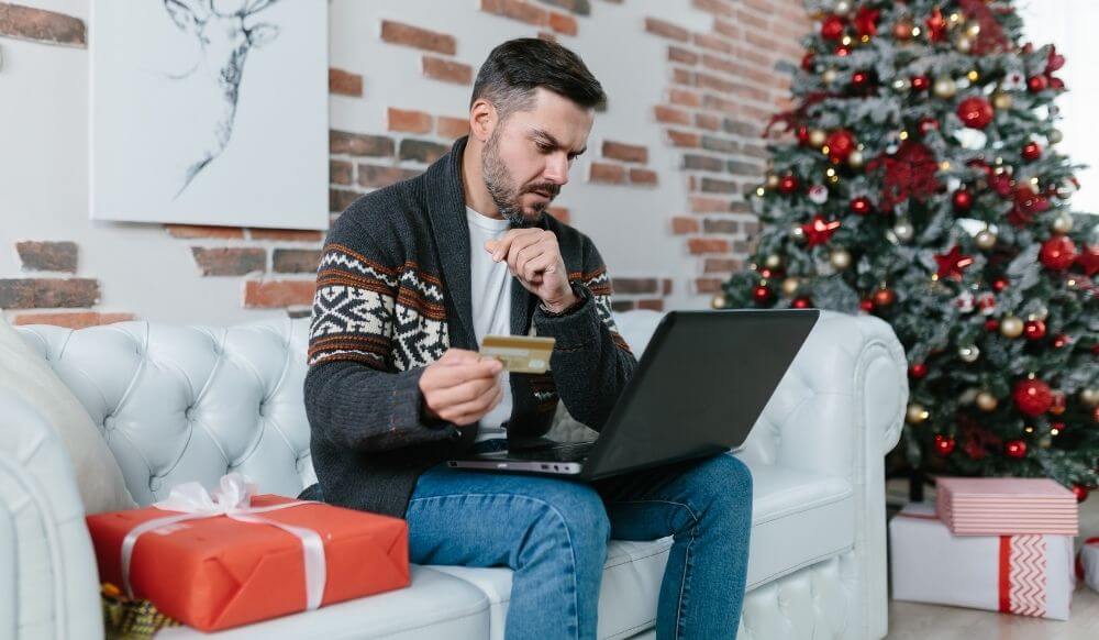 man-with-beard-sitting-couch-during-new-year-holidays-nervous-worried-trying-get-loan-online-using-laptop-credit-card