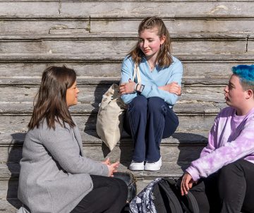 three young people sitting on steps talking