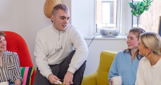 four young people sitting inside chatting